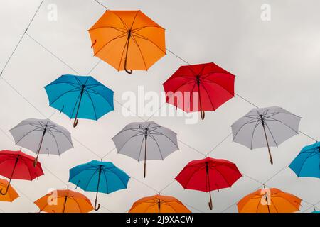 Bunte Regenschirme hängen beim Outdoor-Festival am bewölkten Himmel Stockfoto