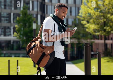 Junger schwarzer Mann in Ohrstöpseln, der in der Stadt telefoniert Stockfoto