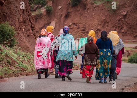 Gruppe von Berberfrauen, die auf einer asphaltierten Straße arbeiten, Ait Blal, Provinz azilal, Atlasgebirge, marokko, Afrika Stockfoto