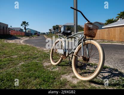 Altes rostiges Fahrrad, das an einem sonnigen Tag an einem Straßenschild gelehnt ist. Stockfoto