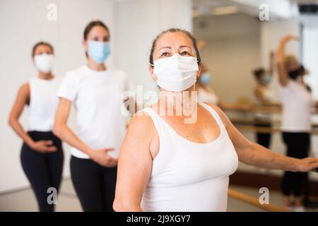 Frauen in Masken üben Ballettbewegungen im Trainingsraum Stockfoto