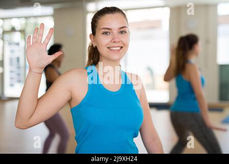 Lächelndes Mädchen, das während des Gruppentrainings kräftigen Schwung übt Stockfoto