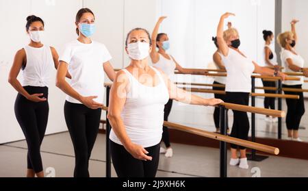 Frauen in Masken üben Ballettbewegungen im Trainingsraum Stockfoto