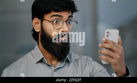 Arabischer indischer junger bärtiger Mann Geschäftsmann hübscher Unternehmer halten Smartphone reden Online-Video-Kommunikation mit Geschäftspartner virtuell Stockfoto