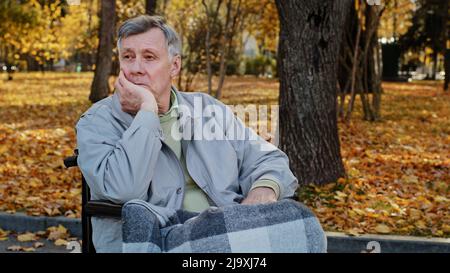 Reifen im Freien verärgert Senior pensionierten kaukasischen Mann Großvater Rentner allein sitzen im Rollstuhl deprimiert nachdenklichen alten männlichen Person im höheren Alter hat Stockfoto