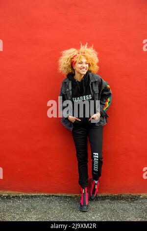 Verrückte blonde Frau, die gegen die Wand steht Stockfoto