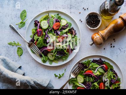 Draufsicht auf Salate mit Salat, Tomaten und Gurken auf zwei Tellern. Stockfoto