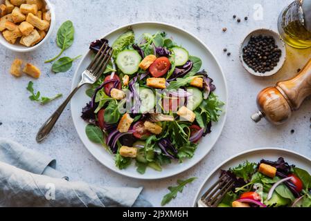 Draufsicht auf Salate mit Salat, Tomaten und Gurken auf zwei Tellern. Stockfoto