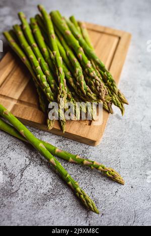 Nahaufnahme der Speere mit frischem Spargel auf dem Schneidebrett auf der Theke. Stockfoto
