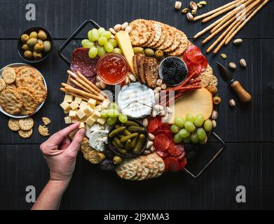 Überreichen Sie die Wurstplatte mit Fleisch, Käse, Obst, Crackern. Stockfoto