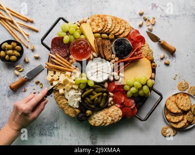 Handprobennahme von Wurstwaren, Käse, Obst, Crackern. Stockfoto