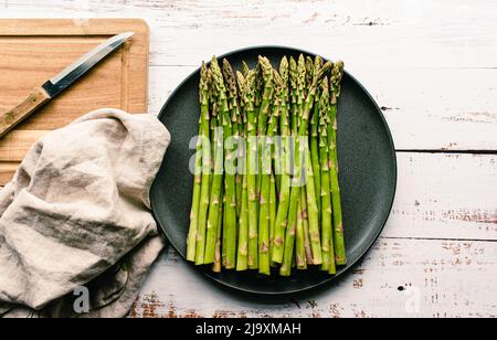 Overhead von Teller mit Speeren von frischem Spargel auf rustikalen weißen Tisch. Stockfoto