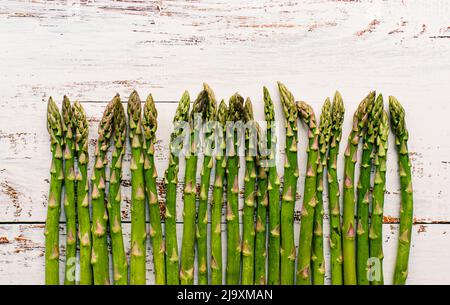 Nahaufnahme von Speeren von frischem Spargel auf rustikalem weißem Holz. Stockfoto