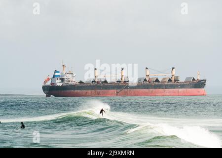 Weite Ansicht eines Surfers vor einem Schiff Stockfoto