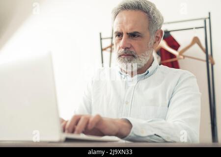 Es ist immer an der Zeit, etwas Neues zu lernen. Bärtiger kaukasischer grauhaariger Geschäftsmann hat seinen Job beendet und ein neues freiberufliches Unternehmen eröffnet. Hochwertige Fotos Stockfoto
