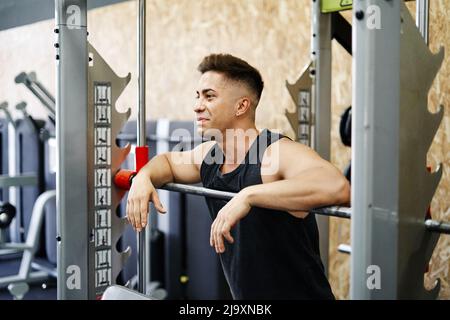 Junger Mann, der sich vom Anheben von Gewichten in einem griffigen Workout Gym erholt Stockfoto