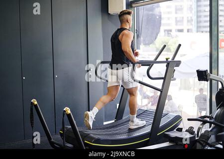 Mann in Sportbekleidung läuft auf dem Laufband, während er im Fitnessstudio trainiert. Stockfoto