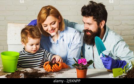 Kleiner Helfer Sohn unterstützt Mutter und Vater beim Pflanzen von Blumen. Familienhaus Gartenarbeit. Pflege der Pflanzen. Stockfoto