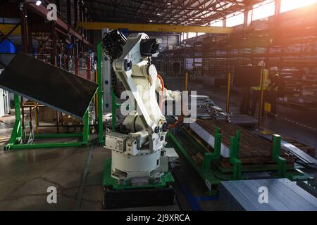 Roboterarm, der mit Metallblech arbeitet. Stockfoto