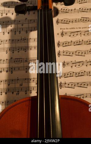 Violine mit Noten hinter. Klassische oder Kammerholz-Geige. Musikinstrument mit seiner Partitur Stockfoto