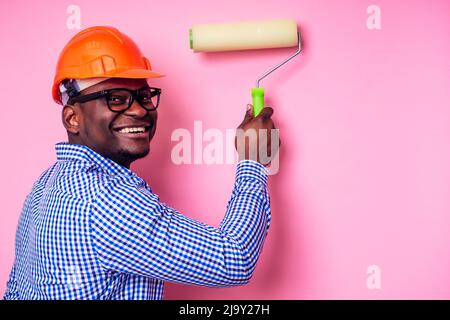 Schwarzer Mann afrikanisch amerikanisch halten Farbe Roller in der Hand malt die Wand in rosa Farbe. Glücklich afrikanischen Baumeister Malerei im Haus, Geschäftsmann Stockfoto