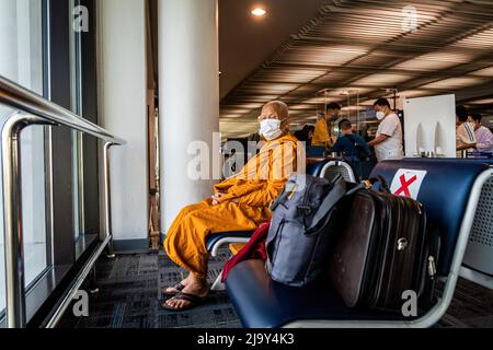 Bangkok, Thailand. 26.. Mai 2022. Ein buddhistischer Mönch mit Gesichtsmaske wartet auf einen Abflug am Don Mueang International Airport (DMK) in Bangkok. Internationale Reisen nach Thailand und inländischer Tourismus im Land werden wieder aufgenommen, da die thailändische Regierung die Einreisebestimmungen im Rahmen ihres Thailand Pass-Programms vereinfacht, so dass internationale Reisende das Land ohne einen schnellen PCR-Test für COVID-19 oder Quarantäne bei der Ankunft betreten können. Die thailändische Regierung hat auch signalisiert, dass die Auflage, Gesichtsmasken im Freien zu tragen, voraussichtlich Mitte Juni 2022 enden wird. Kredit: SOPA Images Limited/Alamy Live Nachrichten Stockfoto