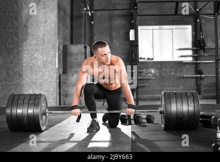 Müde muskulöse Mann gewinnen eine Langhantel in der Turnhalle. Vorbereitung auf die Deadlift-Übung. Stockfoto