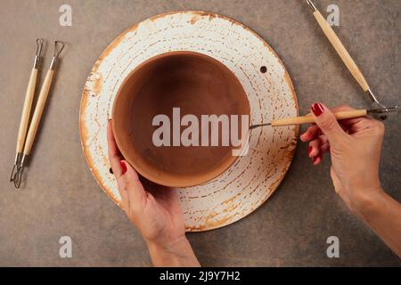 Nahaufnahme schmutziger Hände eines Mannes, einer Töpferin, die einen Tonerde-Krug auf dem Kreis des Töpfers im Werkstatt-Copyspace-Studio kreiert Stockfoto