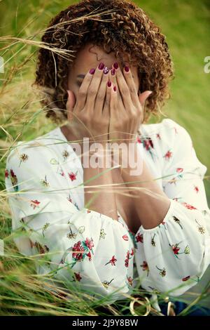 Schwarze Frau versteckt Gesicht mit weinenden Händen Stockfoto