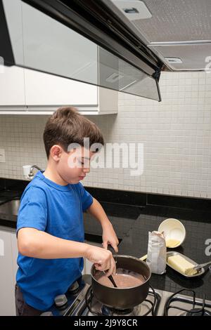 8 Jahre alt in der Küche, die einen brasilianischen Süßen, brigadeiro (Brigadier), herstellte. Stockfoto