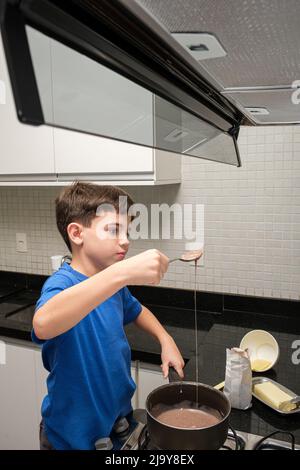 Kind mit einem Löffel, der die Textur von brigadeiro überprüft, einem brasilianischen sweet vertical Foto. Stockfoto