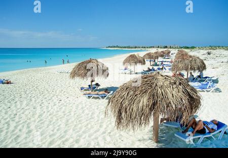 Touristen unter Sonnenschutzschirmen am Strand bei Cayo Largo, Kuba, Karibik | Touristen unter Sonnenschirmen am Strand von Cayo Largo, Kuba, Karibik Stockfoto