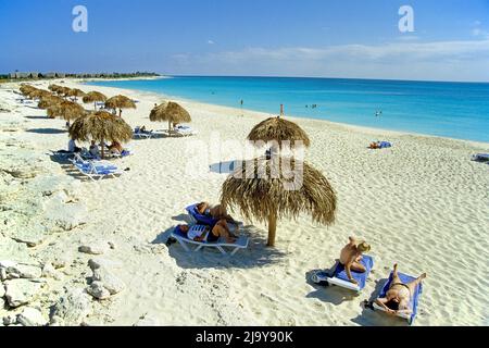 Touristen unter Sonnenschutzschirmen am Strand bei Cayo Largo, Kuba, Karibik | Touristen unter Sonnenschirmen am Strand von Cayo Largo, Kuba, Karibik Stockfoto