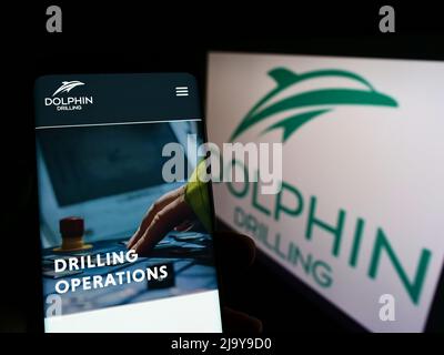 Person, die Smartphone mit Website der Firma Dolphin Drilling Holdings Limited auf dem Bildschirm vor dem Logo hält. Konzentrieren Sie sich auf die Mitte des Telefondisplays. Stockfoto