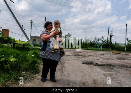 Soledar, Ukraine. 24.. Mai 2022. Eine Mutter mit ihrem Kind in Soledar. Soledar ist eine Stadt der Region Donetsk, die von russischer Artillerie gehämmert wird, da sie sich entlang der entscheidenden Straße befindet, die aus dem belagerten Severodonetsk führt. Kredit: SOPA Images Limited/Alamy Live Nachrichten Stockfoto