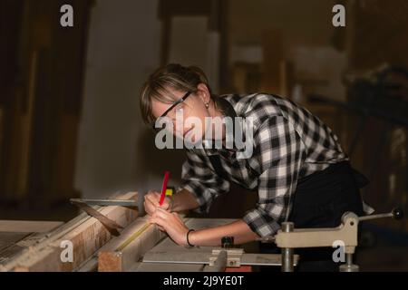 Zimmerfrau, die eine Holzdiele vermessen hat Stockfoto
