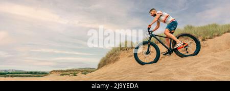 Mann, der mit einem fetten Fahrrad durch die Stranddünen fährt Stockfoto