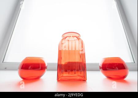 Drei leere rote Glasvasen auf der Fensterbank. Stockfoto