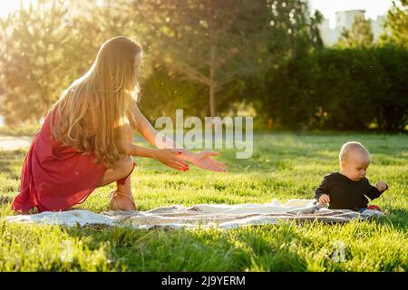 Kleiner Junge zusammen mit Mutter auf einer Decke im Park im Sommer Stockfoto