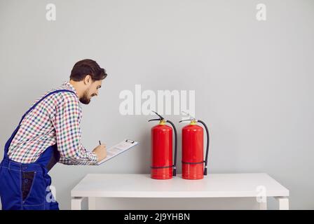 Brandschutzinspektor notiert sich bei der Überprüfung der Feuerlöscher im Gebäude Stockfoto