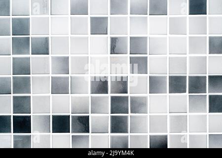 Weiße und graue kleine Keramikfliesen an einer Badezimmerwand, moderne saubere Fliesen als Textur oder Hintergrund Stockfoto