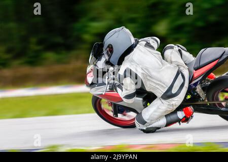 Motorrad-Praxis lehnt sich in eine schnelle Ecke auf der Strecke Stockfoto