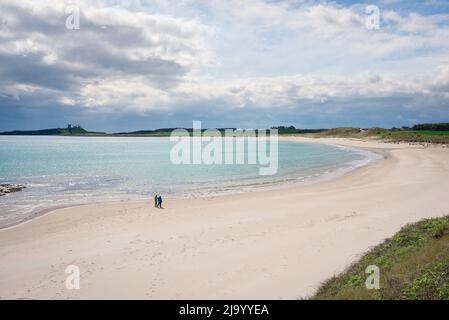 Northumberland Beach, Blick im späten Frühling auf ein Paar, das alleine auf dem einsamen Strand in Embleton Bay, Northumberland, England, Großbritannien, läuft Stockfoto