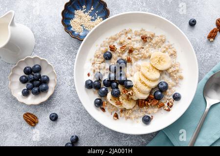 Haferbrei mit Banane, Heidelbeeren, Pekannüssen und Sesam Stockfoto