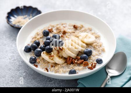 Haferbrei mit Banane, Heidelbeeren, Pekannüssen und Sesam Stockfoto