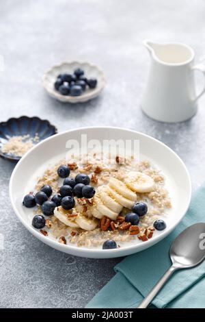 Haferbrei mit Banane, Heidelbeeren, Pekannüssen und Sesam Stockfoto