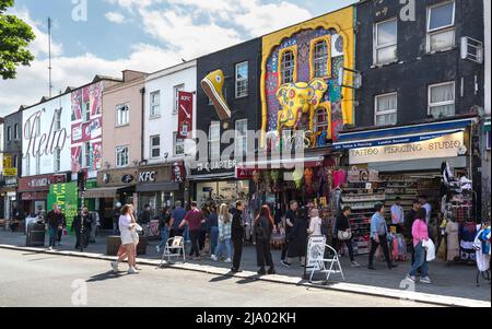 Shopper und Touristen, die entlang der Camden High Street mit ihren schrulligen, farbenfrohen und prunkvollen Geschäften gehen, Stockfoto