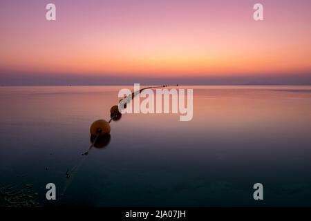 Seascape zeigt einen rosa Sonnenaufgang bei schwachem Licht über dem ruhigen Wasser des Mar Menor in der Region Murcia, Spanien. Stockfoto