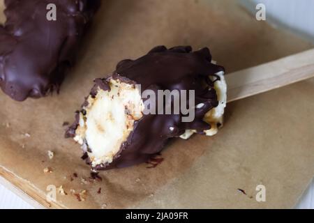 Bananen mit Erdnüssen auf einem Stock. Ein Stück wird abgebissen, die innere Füllung ist sichtbar. Nahaufnahme. Stockfoto