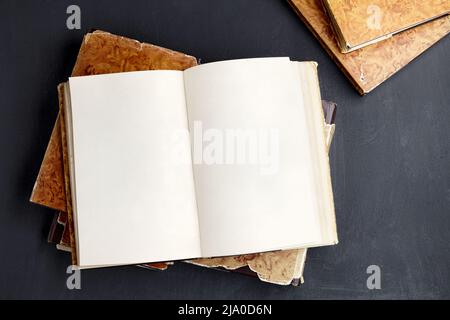 Öffnen Sie ein Vintage-Buch oder Notizbuch in einer Schutzumschlag auf einem Stapel alter schäbiger Bücher Stockfoto